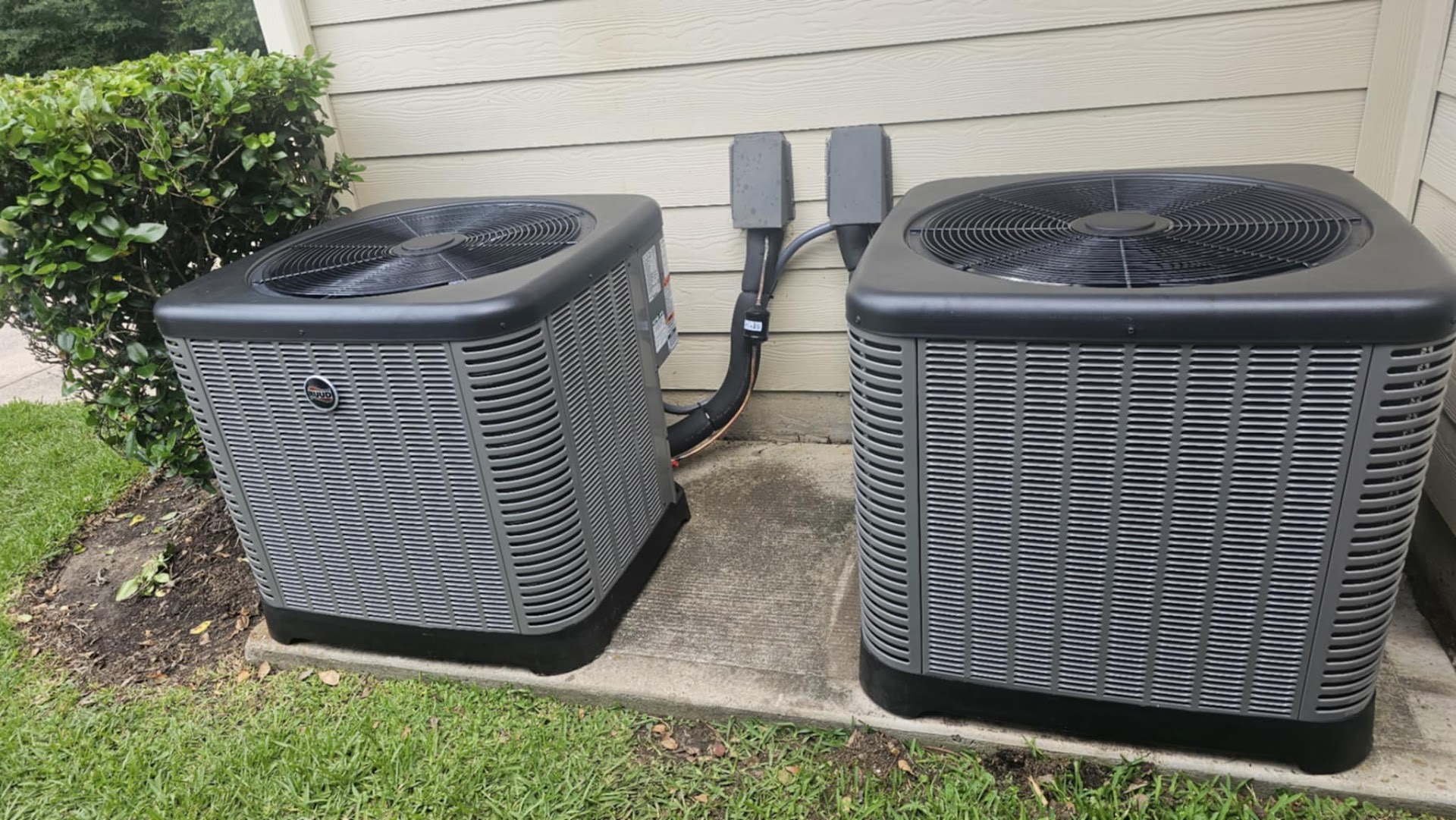 Two matching condensers installed side by side at a home